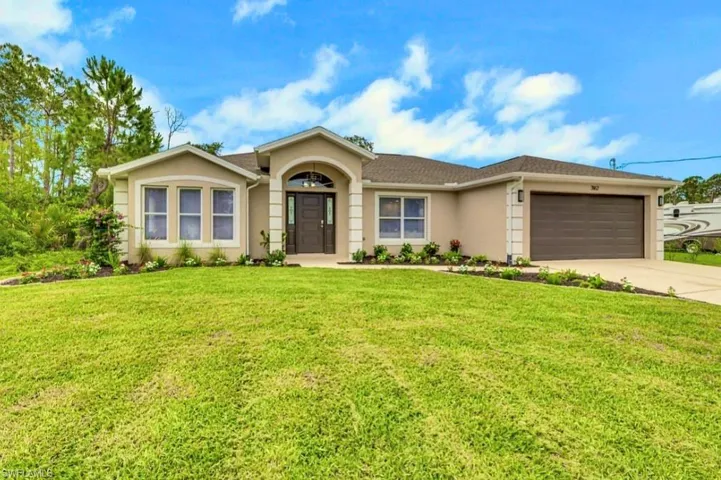 Contemporary stucco exterior with a dark brown entry door, arched portico, three-panel bay window, a two-car garage, and a lush green lawn