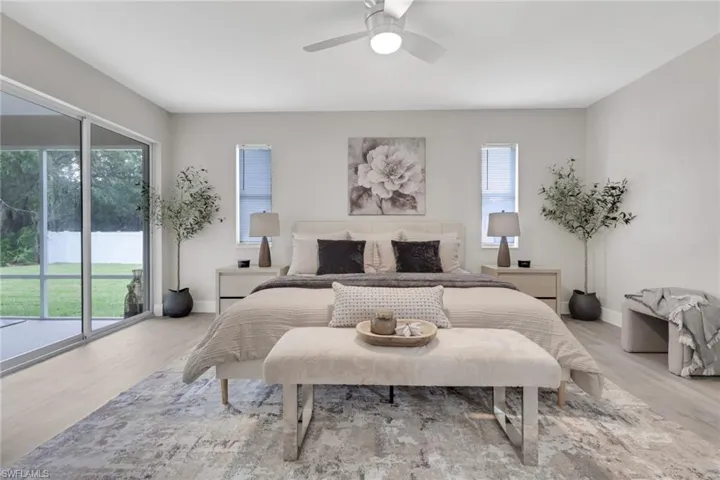 Spacious room featuring light wood-finish flooring, a ceiling fan with integrated lighting, and multiple windows