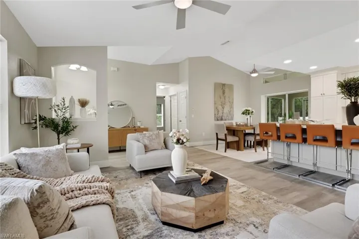 Open-concept living area featuring vaulted ceilings, wood-finish flooring, recessed lighting, and a ceiling fan
