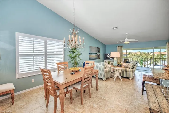 Dining space with ceiling fan with notable chandelier, vaulted ceiling, and light tile patterned floors
