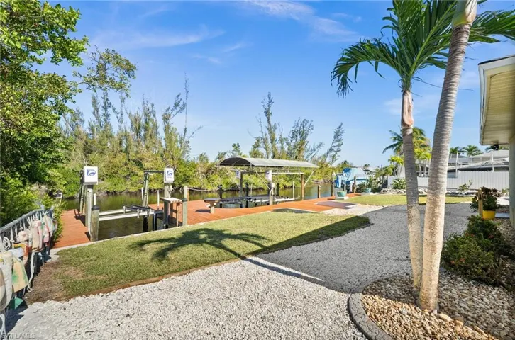View of play area with a water view, a dock, and a lawn
