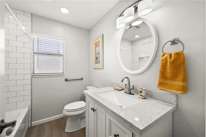 Full bathroom featuring hardwood / wood-style floors, vanity, toilet, and tiled shower / bath