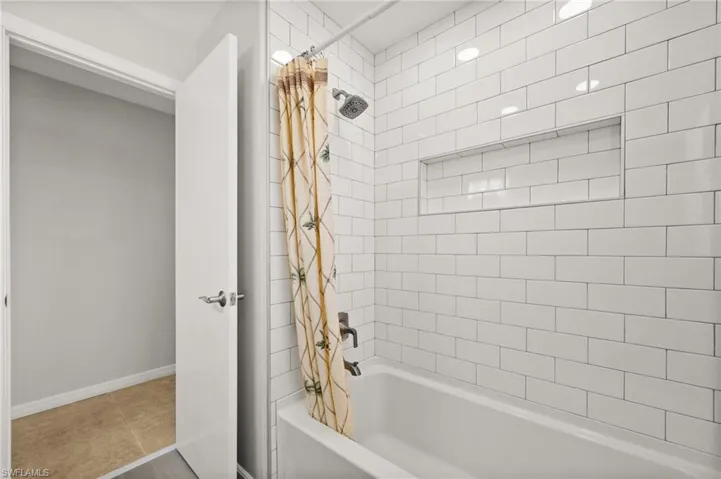 Bathroom featuring tile patterned flooring and shower / bathtub combination with curtain