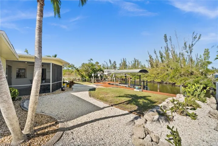 View of yard with a sunroom, a boat dock, and a water view