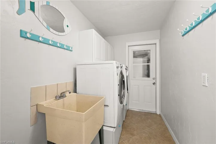 Washroom featuring cabinets, separate washer and dryer, sink, and light tile patterned floors