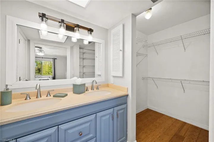 Bathroom with hardwood / wood-style floors, ceiling fan, and vanity