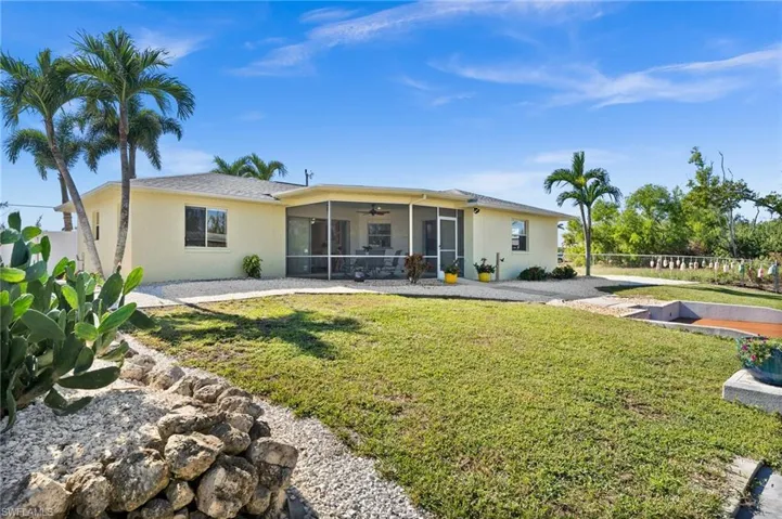 Rear view of property with ceiling fan, a lawn, and a sunroom