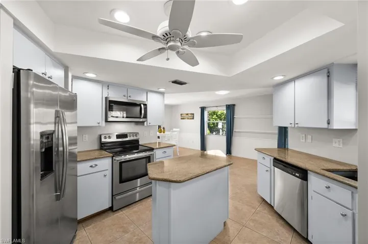 Kitchen with a center island, white cabinets, stainless steel appliances, and light tile patterned floors