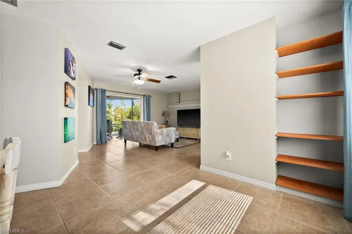 Living room with ceiling fan and light tile patterned flooring