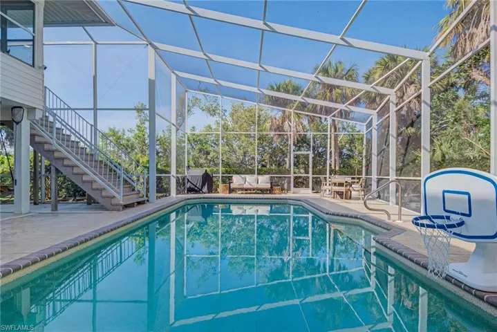 Swimming pool featuring stairs, a long patio area under the house that is shaded and screened-in Fully upgraded pool area with new saltwater pool system, heater, pump, and raised pool equipment. Large screened-in patio area and bonus rooms including bathroom on lower level.
