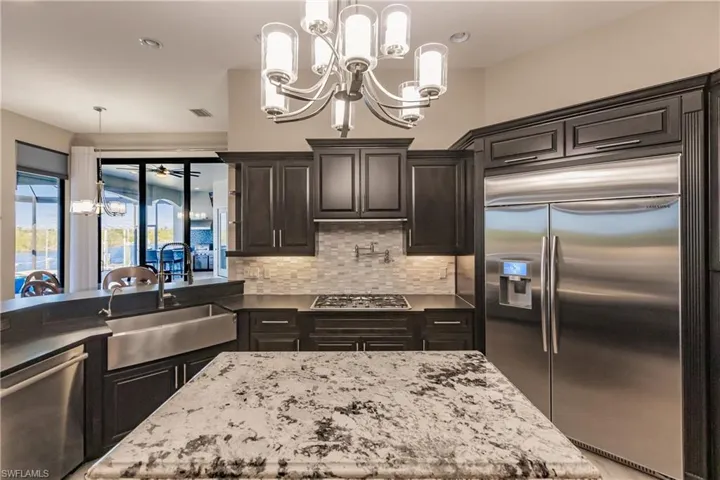 Kitchen with granite countertops, with stainless steel finishes to include a 48" Samsung Fridge, Bosch dishwasher and Propane cook top with pot filler, and tasteful backsplash