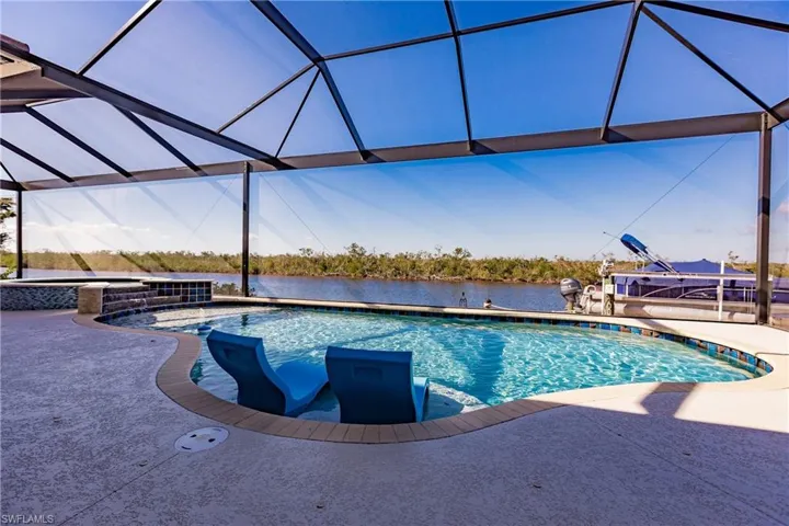 View of swimming pool featuring waterfall into the spa, a water view, and a lanai