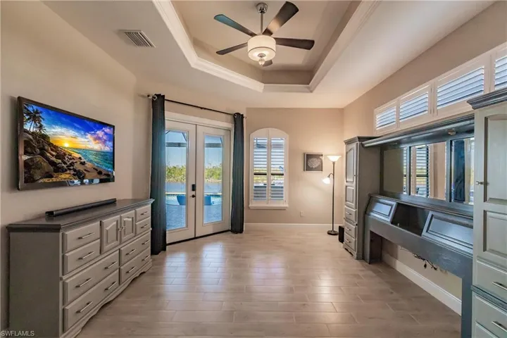 Doorway to outside featuring ceiling fan, a tray ceiling, and french doors