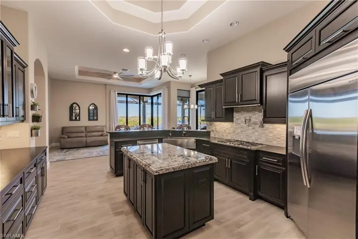 Kitchen featuring sink, a center island, hanging light fixtures, a raised ceiling, and appliances with stainless steel finishes