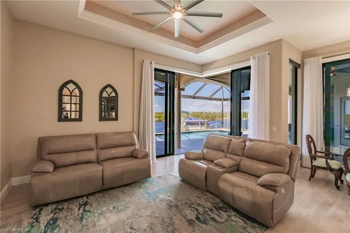 Living room with a tray ceiling, ceiling fan, and light hardwood / wood-style floors