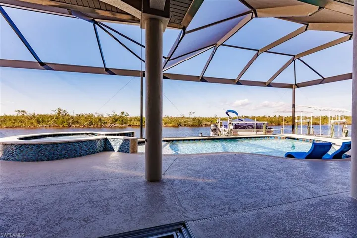 View of pool featuring a lanai, a 10 person hot tub, water view, and a patio
