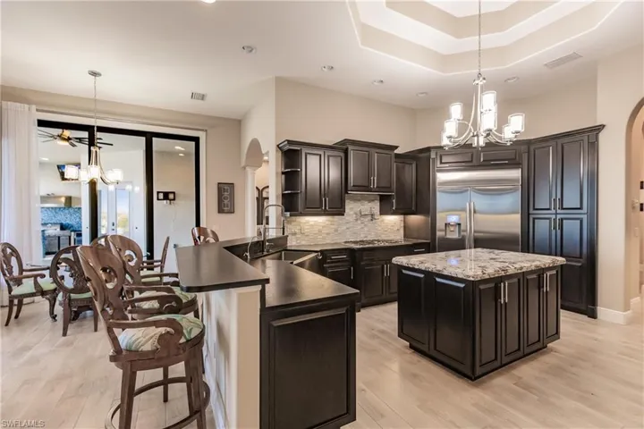 Kitchen with pendant lighting, ceiling fan with notable chandelier, sink, 48" Samsung Refrigerator, and kitchen peninsula