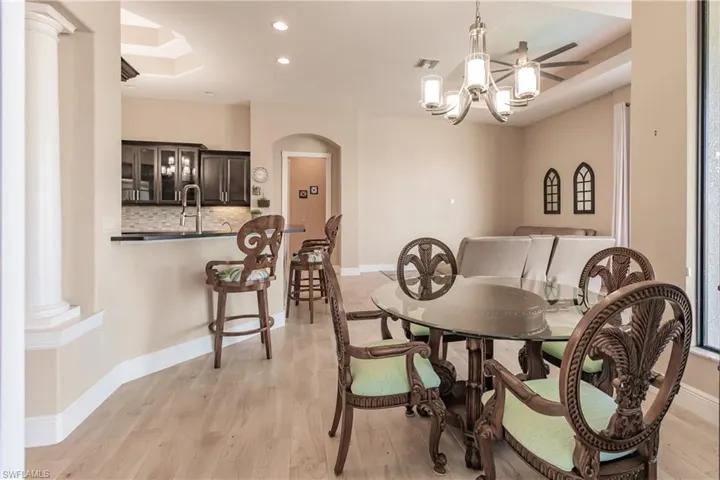 Dining area with a chandelier, light hardwood / wood-style floors, decorative columns, and sink