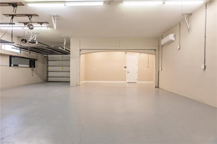 Garage with a wall mounted AC and a garage door opener
