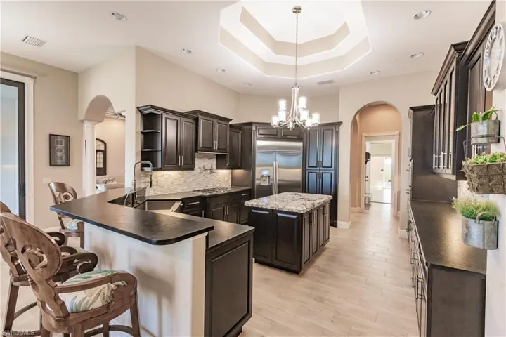 Kitchen with sink, 48" Samsung Refrigerator, kitchen peninsula, decorative light fixtures, and a kitchen island