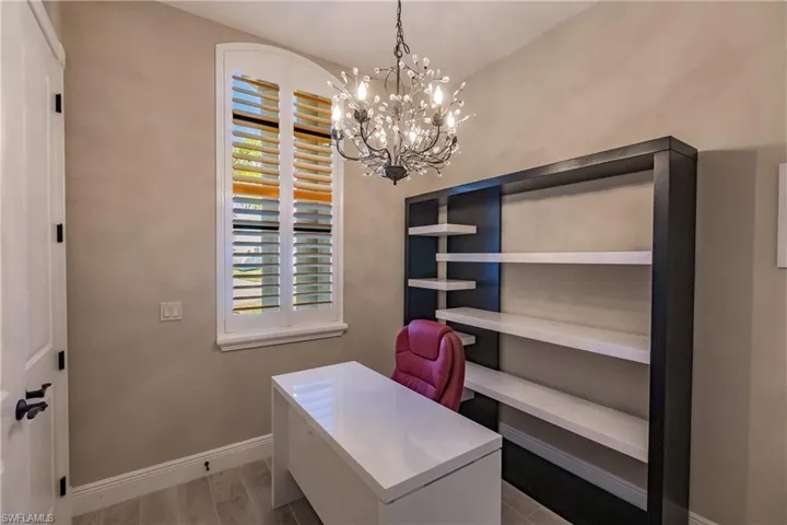 Office with light wood-type flooring and a notable chandelier