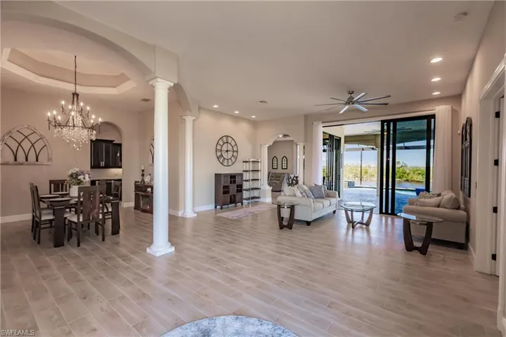 Living room with 9 ft impact glass doors, light hardwood / wood-style floors, and ornate columns
