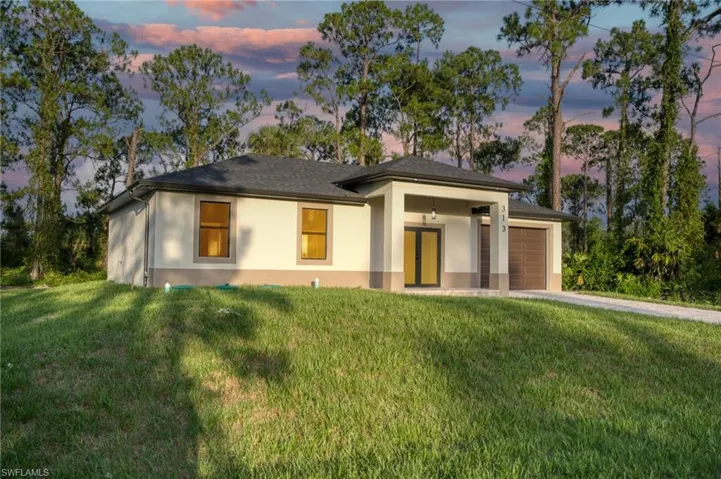 Prairie-style house featuring stucco siding, a front yard, driveway, and an attached garage