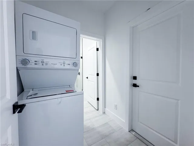 Laundry room with stacked washer / drying machine and baseboards