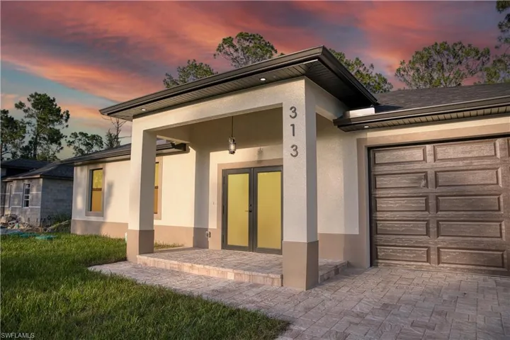View of front of property featuring stucco siding, a garage, and decorative driveway
