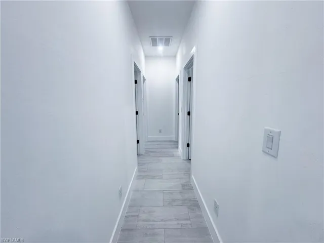 Hallway featuring light marble finish flooring and baseboards