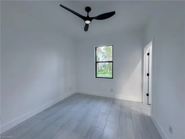 Empty room featuring a ceiling fan and baseboards