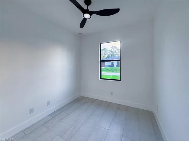 Empty room featuring a ceiling fan and baseboards