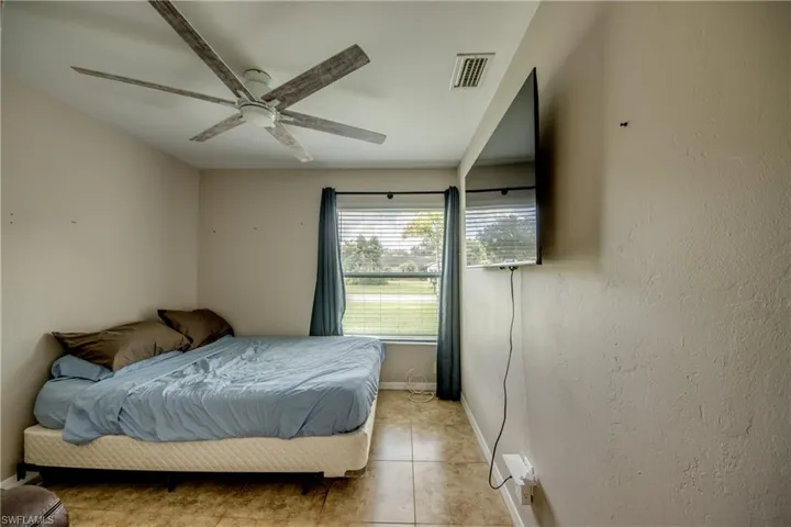 Tiled bedroom featuring ceiling fan