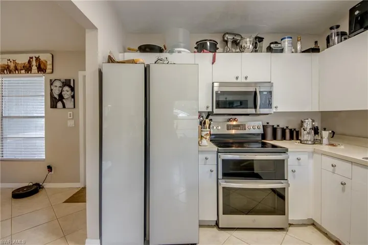 Kitchen featuring stainless steel appliances, light tile patterned floors, and white cabinets
