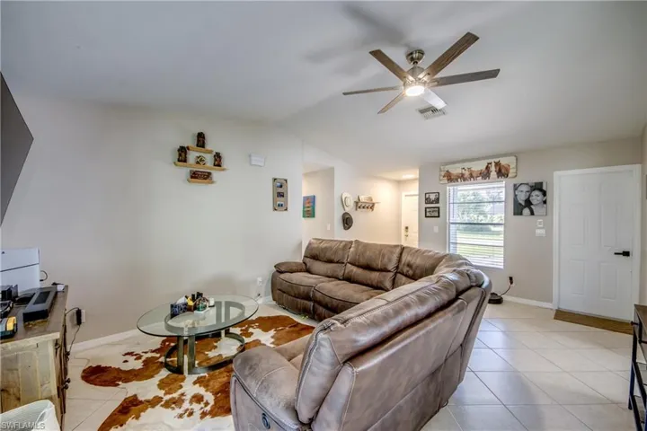 Living room featuring ceiling fan, light tile patterned floors, and vaulted ceiling