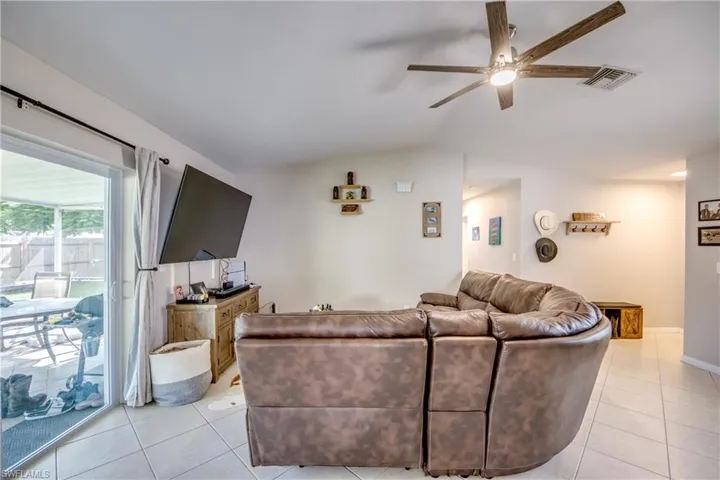 Tiled living room with ceiling fan and vaulted ceiling
