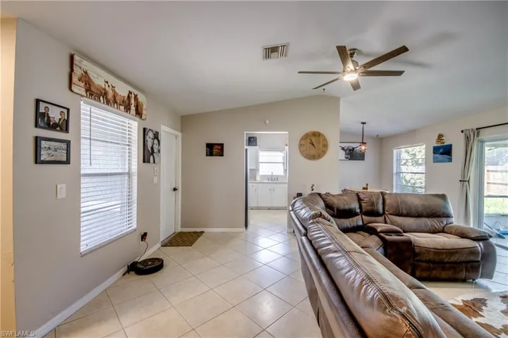 Tiled living room featuring ceiling fan and vaulted ceiling