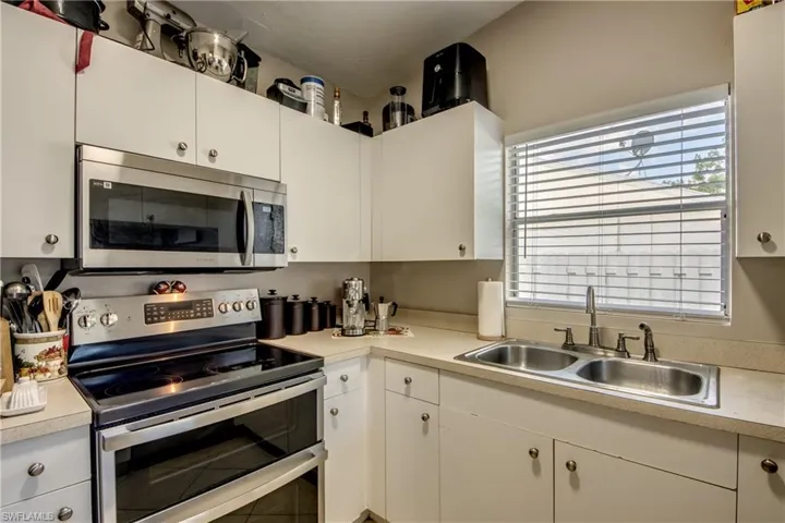 Kitchen featuring appliances with stainless steel finishes, white cabinetry, and sink