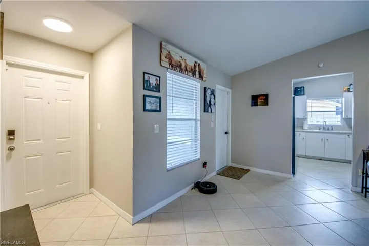Tiled entryway featuring lofted ceiling and sink