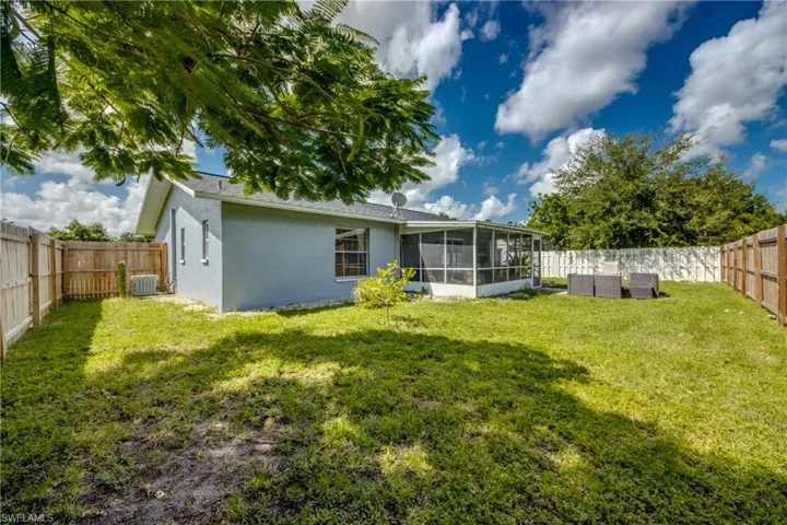 Back of property with a yard, cooling unit, and a sunroom
