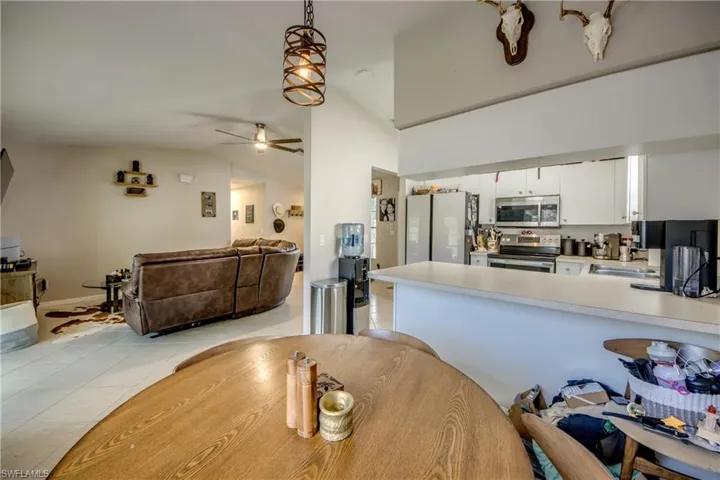 Kitchen featuring white cabinets, vaulted ceiling, appliances with stainless steel finishes, ceiling fan, and pendant lighting