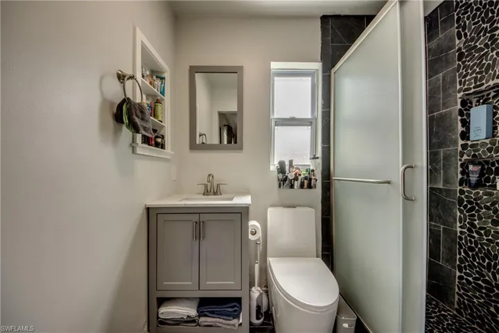 Bathroom featuring vanity, toilet, and a shower with door