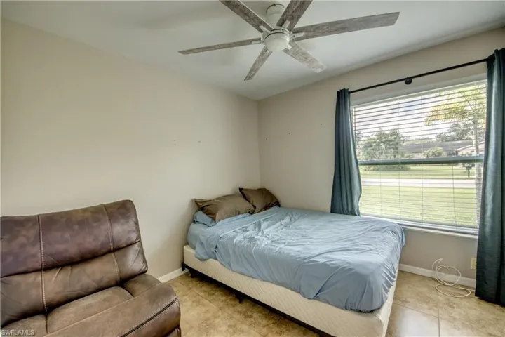 Tiled bedroom with ceiling fan and multiple windows