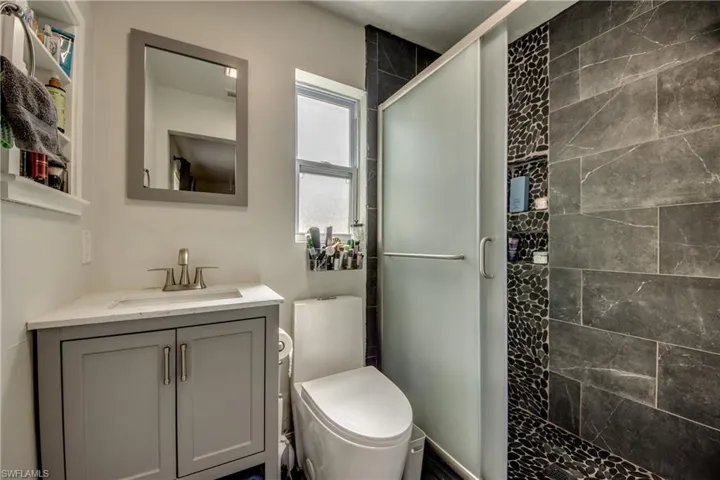 Bathroom with vanity, toilet, and an enclosed shower