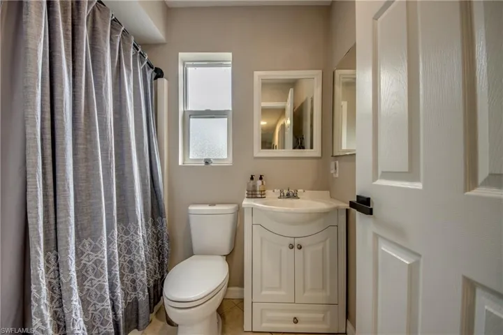 Bathroom with tile patterned floors, a shower with shower curtain, toilet, and vanity