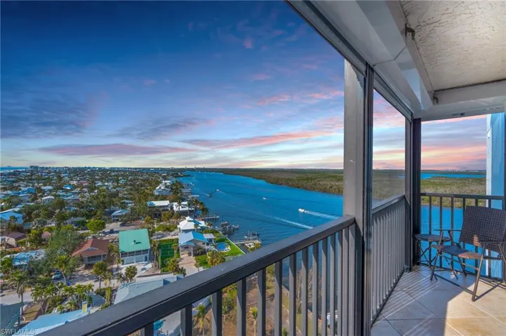 VIRTUALLY ENHANCED - Balcony at dusk featuring a water view
