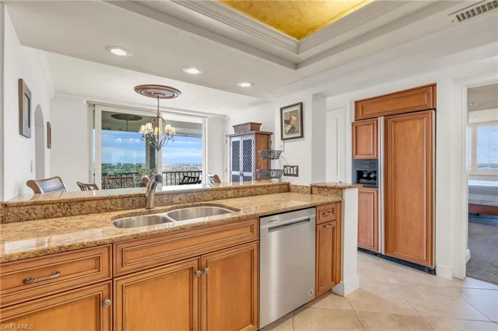 Kitchen with sink, an inviting chandelier, stainless steel dishwasher, pendant lighting, and a tray ceiling / vrtually enhanced image