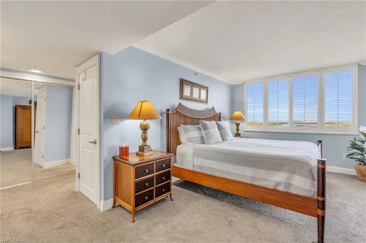 Bedroom with light colored carpet, crown molding, and a closet / virtually enhanced image