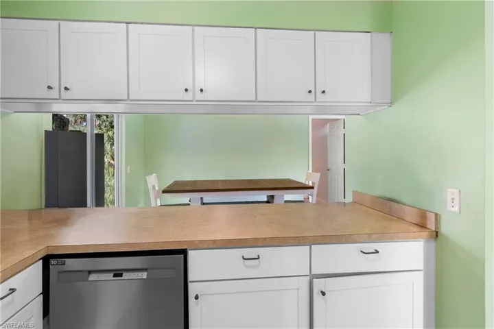 Kitchen featuring dishwasher, light countertops, and white cabinetry