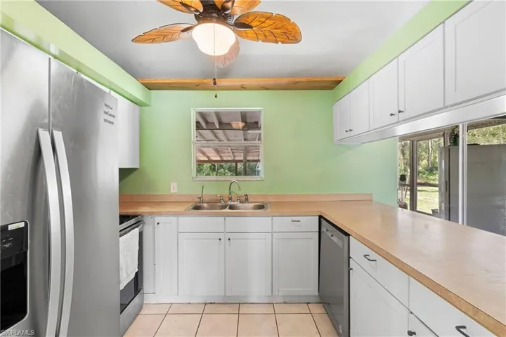 Kitchen with stainless steel appliances, white cabinets, light countertops, and light tile patterned floors
